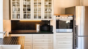 A kitchen with white cabinets, a black tiled backsplash, a stainless steel refrigerator, and a built-in oven. - Beautiful home in Saltum with WiFi (Saltum)