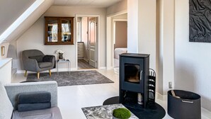 A modern living room with a sofa, a small table with a plant, a fireplace, and a staircase leading to another room. - Beautiful home in Saltum with WiFi (Saltum)