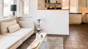 A modern living room with a sofa, a decorative table, a rug, and a kitchen area with cabinets and a countertop. - Beautiful home in Saltum with WiFi (Saltum)