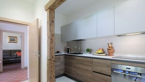 Una cocina moderna con armarios de madera, horno empotrado y una encimera con cafetera y fruta.