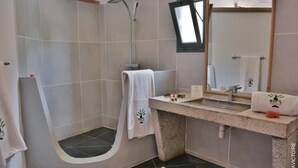 A bathroom with a shower, a sink with a mirror, and a towel rack. - Hotel Residence Sarimanok (Nosy Be)