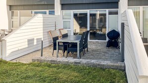 A patio with a table and chairs, a grill, and a sliding glass door leading to an indoor area. - Amazing home in Vestervig with sauna (Vestervig)