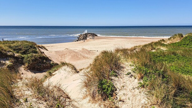 A beach with a stone wall, sand dunes, and vegetation. - Amazing home in Vestervig with sauna (Vestervig)