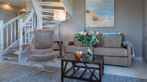 Ein Wohnzimmer mit Treppe, einem Sofa, einem Couchtisch und einem Bild an der Wand.