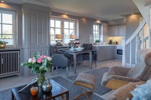 A spacious kitchen with a dining area, a staircase, and a living room with a fireplace. - Heefwai 2-W6 - Heefwai 6 - for two people (Sylt-Ost)