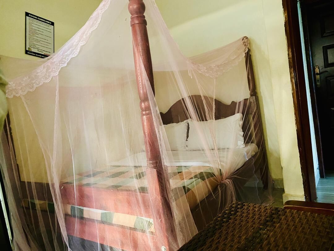 A bed with a wooden frame and a mosquito net.
