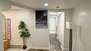 Un salon moderne avec un canapé, une plante en pot, un tableau accroché au mur et un couloir menant à une autre pièce.
