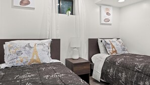 Une chambre d’hôtel avec deux lits, une fenêtre avec des rideaux, une table de chevet avec une lampe et des œuvres d’art accrochées au mur.