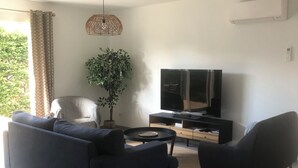 Una sala de estar moderna con sofá, sillón, televisor y una planta en maceta.