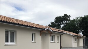 Un edificio con techo de tejas, varias ventanas y un camino de entrada de grava.