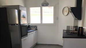 Una cocina con refrigerador, horno y ventana con vista a una valla.