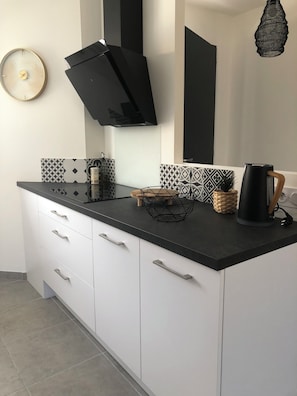 A modern kitchen with white cabinets, a black countertop, and a geometric backsplash. - House in Le Teich; nature and beaches nearby (Le Teich)
