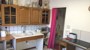 A kitchen with wooden cabinets, a sink, a countertop, and a shower curtain. - Ground floor cottage Gite with disabled access-Swimming pool-Jacuzzi (Le Poujol-sur-Orb)