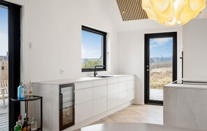 Eine moderne Küche mit einem großen Fenster, einem eingebauten Geschirrspüler und Blick ins Freie.