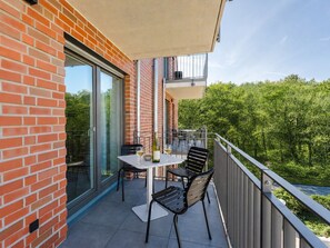 A balcony with a table and chairs, a bottle of wine, and a glass. - MEERholung FeWo 3.2 - Comfortable vacation apartment close to the beach - MEERholung (Cuxhaven)