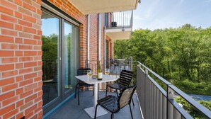 En balkon med et bord, stole, en vinflaske og et glas.