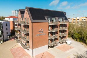 Un immeuble de plusieurs étages, construit en briques, avec un toit plat, des balcons et un logo sur le côté.