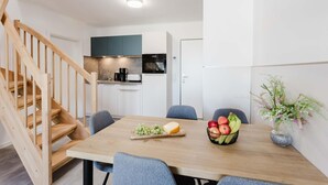 Een moderne keuken met witte kasten, een houten trap en een eethoek met een tafel gedekt voor twee personen.