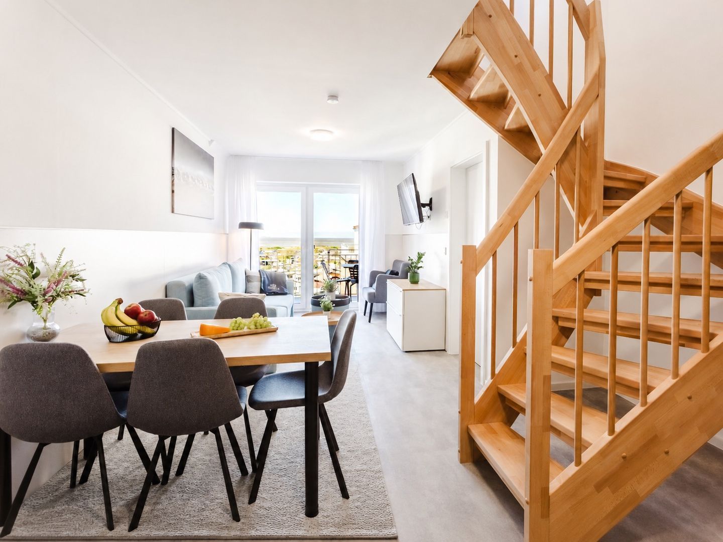 Een modern interieur met een eethoek, een trap en uitzicht op het omliggende landschap.