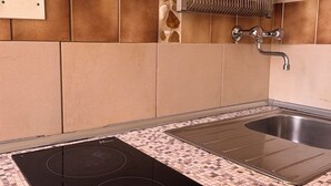 A kitchen with a black induction cooktop, a stainless steel sink, and a tiled backsplash. - 1.5 km from the AOI airport, comfortable studio apartments for your needs. (Falconara Marittima)