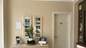 A reception desk with a plant, framed pictures, and a door with a Wi-Fi sign. - 1.5 km from the AOI airport, comfortable studio apartments for your needs. (Falconara Marittima)