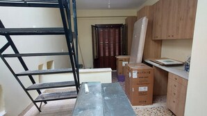 A kitchen with wooden cabinets, a countertop, and a staircase with metal railings. - Platanos Studio - Old Town Rethymno (Rethymno)