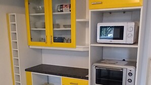 Une cuisine avec des meubles blancs, un four à micro-ondes et un grille-pain.