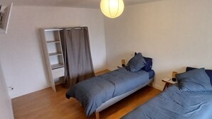 Une chambre avec deux lits, une armoire, une échelle et un luminaire suspendu.