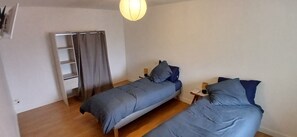 Ein Schlafzimmer mit zwei Betten, einem Kleiderschrank, einer Leiter und einer Pendelleuchte.