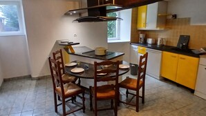 Une cuisine compacte comprenant une table à manger, des chaises, une cuisinière et des placards jaunes.