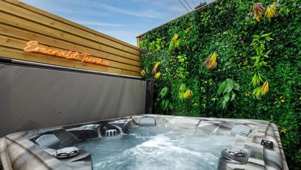 Un jacuzzi con pared de madera y un letrero de neón que dice 'Emerald Terrace'.