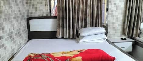 A hotel room with a bed, a nightstand, a mirror, and curtains.
