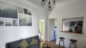 A modern living room with a sofa, a coffee table, and a kitchen area with stools. - The Little House on the River (Castel Dè Ratti)