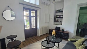A living room with a sofa, two bar stools, a coffee table, a mirror, a bookshelf, and a door leading to a balcony. - The Little House on the River (Castel Dè Ratti)