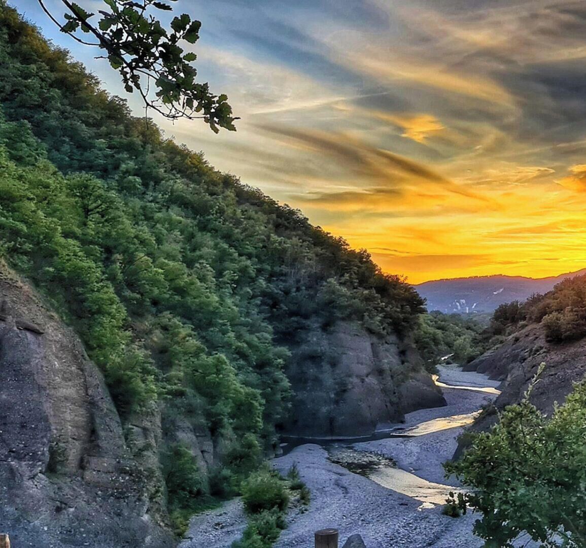 Eine natürliche Landschaft mit Fluss, felsigem Gelände und üppiger Vegetation.
