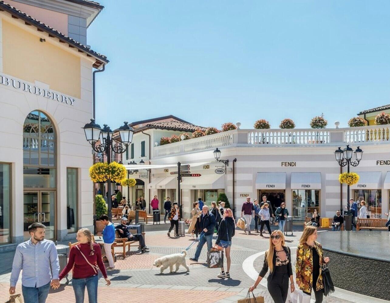 Una zona comercial con tiendas Burberry, Fendi y un edificio blanco con un letrero.