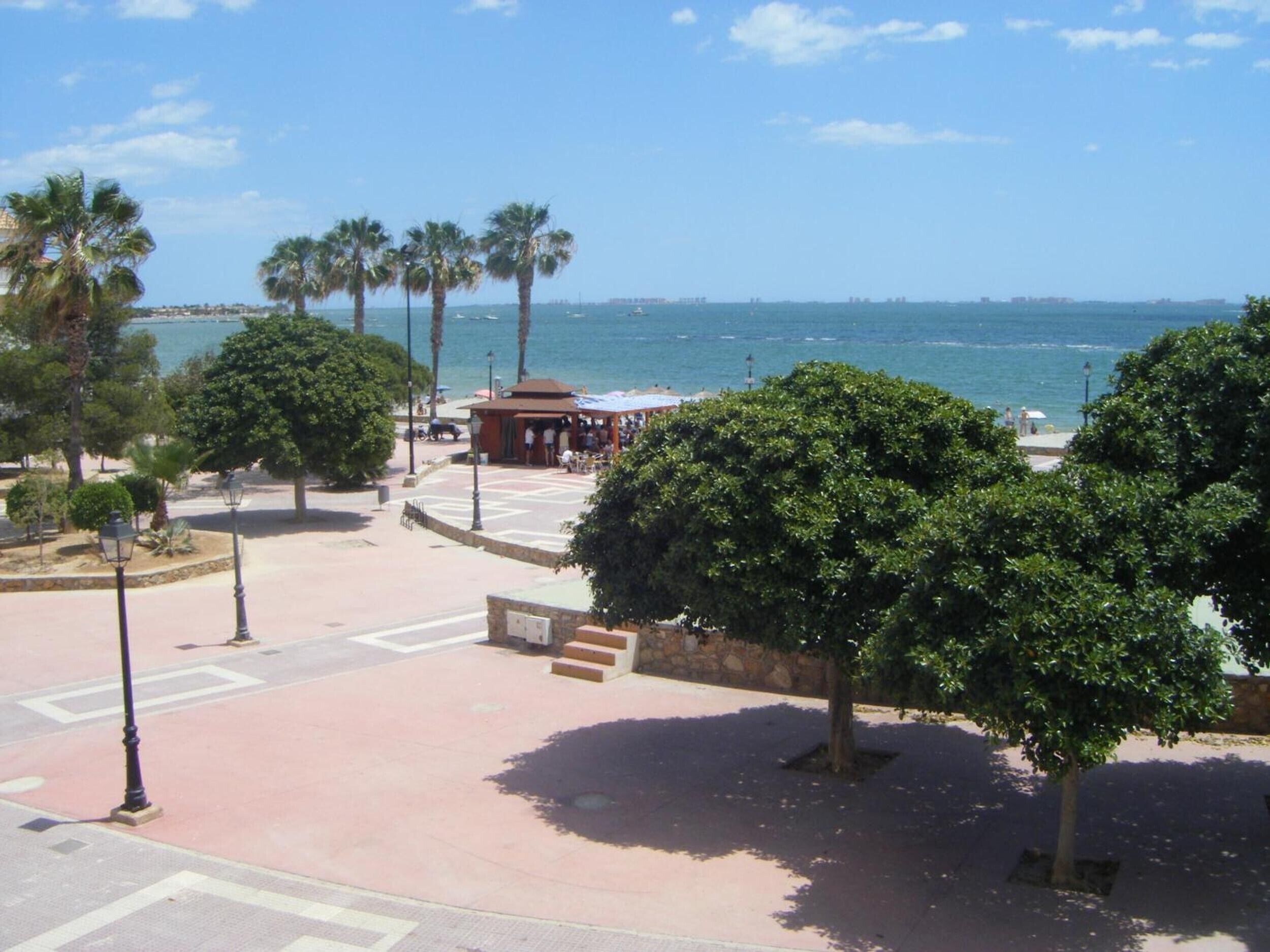 Una passeggiata costiera con palme, una piccola rivendita e vista sul mare.