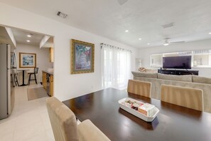 Ein modernes Wohnzimmer mit Esstisch, Sofa, Fernseher und Küchenzeile.