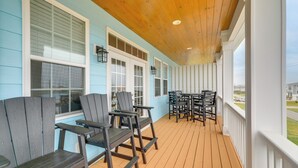 A covered porch with wooden flooring, blue walls, and white trim. There are several Adirondack chairs and a table with chairs. - Hot Tub, Waterway/Ocean Views! Sneads Ferry Escape (Sneads Ferry)