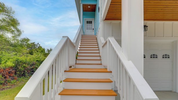 A staircase leading to a white door with a blue accent, surrounded by greenery. - Hot Tub, Waterway/Ocean Views! Sneads Ferry Escape (Sneads Ferry)