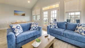 A living room with two blue sofas, a wooden coffee table, and a painting on the wall. - Hot Tub, Waterway/Ocean Views! Sneads Ferry Escape (Sneads Ferry)
