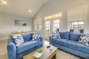 Ein Wohnzimmer mit zwei blauen Sofas, einem Holztisch und einem Bild an der Wand.