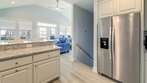 A kitchen with white cabinets, a stainless steel refrigerator, and a granite countertop. - Hot Tub, Waterway/Ocean Views! Sneads Ferry Escape (Sneads Ferry)