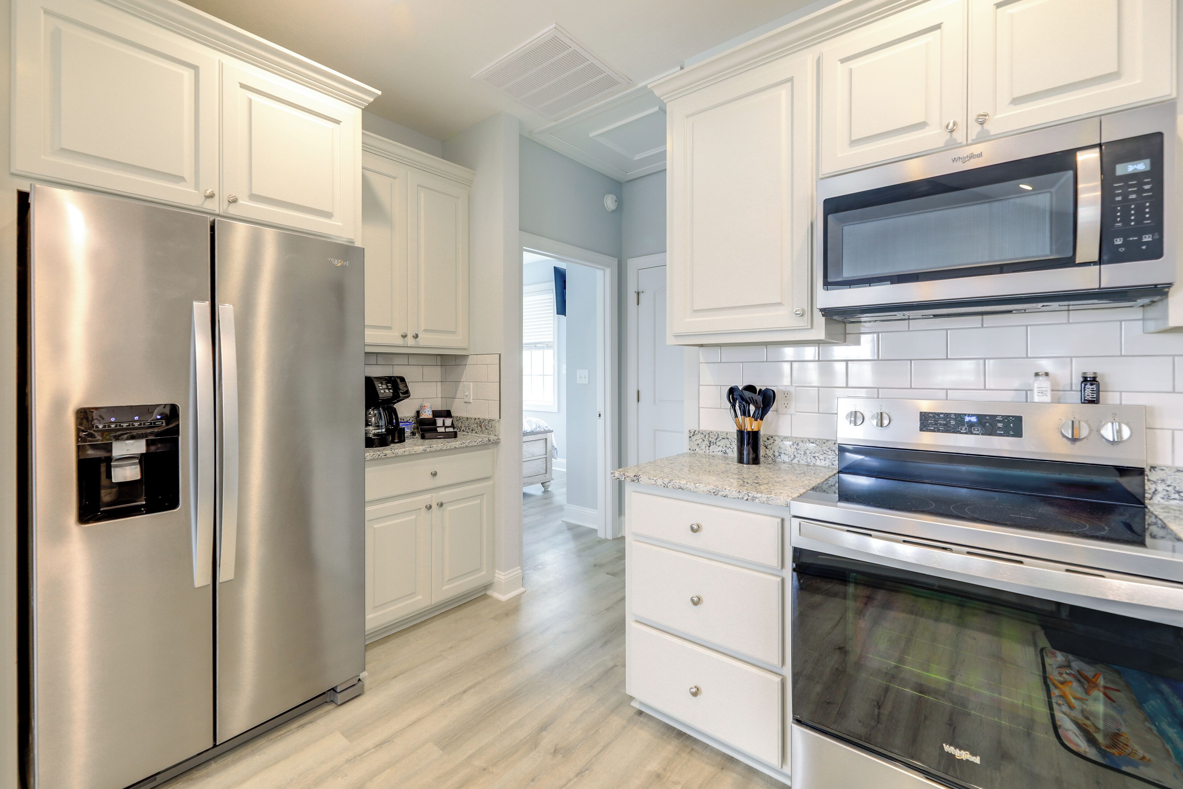 A modern kitchen with white cabinetry, stainless steel appliances, and a tiled backsplash.