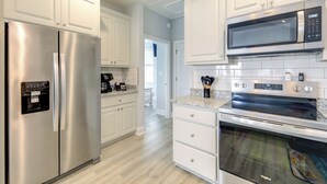 A modern kitchen with white cabinetry, stainless steel appliances, and a tiled backsplash. - Hot Tub, Waterway/Ocean Views! Sneads Ferry Escape (Sneads Ferry)
