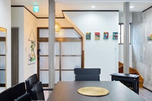 Un salón de conferencias con una larga mesa, sillas, un mantel tejido y una obra de arte en la pared.