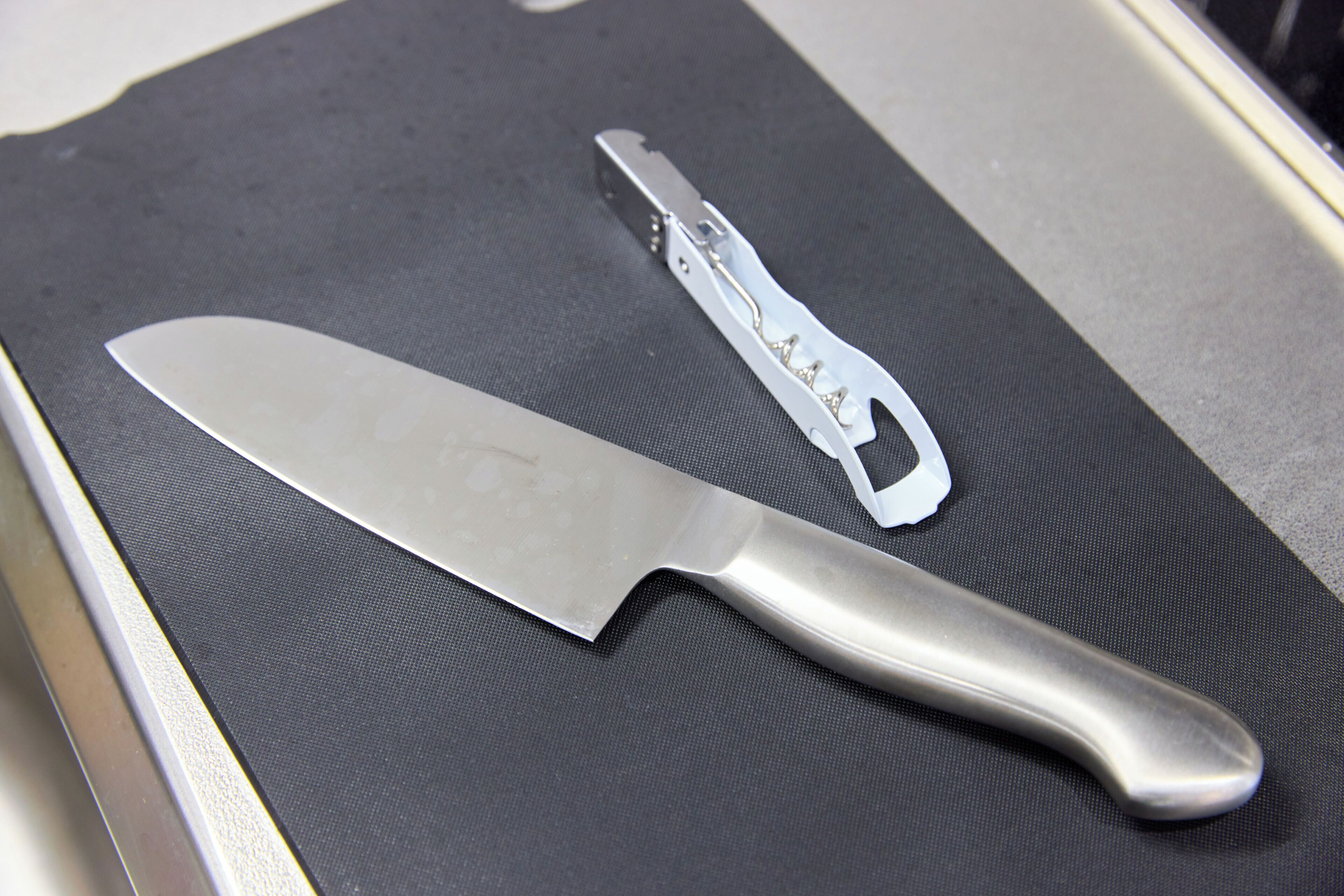 A kitchen counter with a knife and a bottle opener.