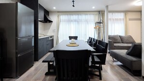 Une cuisine moderne avec une table à manger, des chaises, un réfrigérateur et un canapé dans l’espace salon.