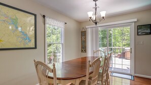 Une salle à manger avec une table et des chaises en bois, une carte accrochée au mur et une vue à travers la porte vitrée.