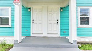 Une maison turquoise avec une porte d’entrée blanche et un panneau indiquant « Entrée interdite ».